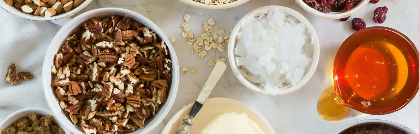 Fresh gourmet cookie baking ingredients including pecans, premium butter, and brown sugar flat-lay